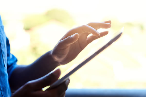 a hand with a finger pointed about to tap on a tablet